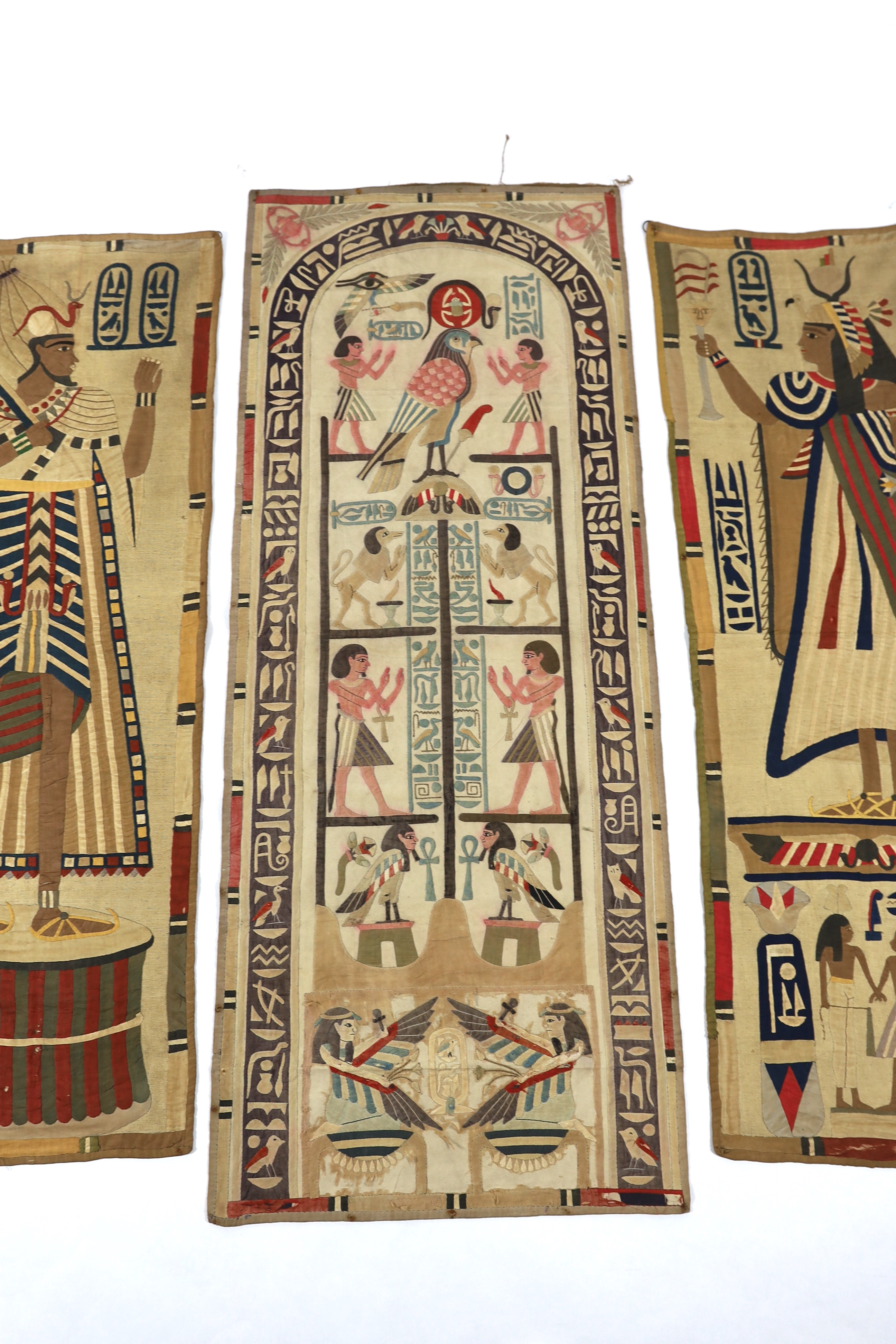 Four 1930’s Egyptian appliqué wall panels, (a pair and two single panels), decorated with various hieroglyphs, Gods and Pharaohs, the panels made for the European market experiencing an Egyptian revival after the discove